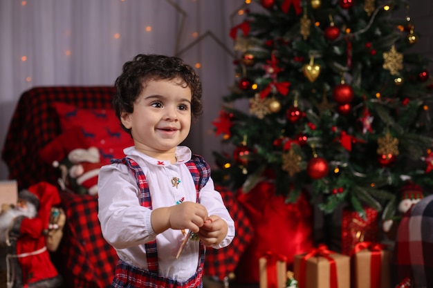 Joyeux Noel et bonne année! Portrait d'un enfant ému en costume de nouvel an dans la salle décorée.