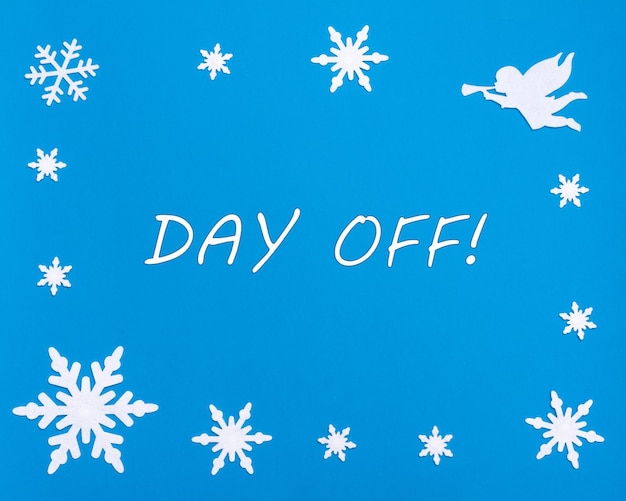 Photo joyeux noël et bonne année texte day off sur fond bleu avec des flocons de neige de noël un ange blanc
