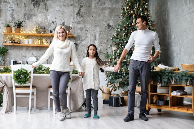 Joyeux Noël Et Bonnes Fêtes. Maman, Papa Et Fille Décorant Le Sapin De Noël.