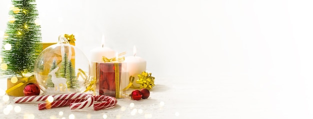 Photo joyeux noël cadeaux de noël bougies surprises sur une table en bois blanc à côté de l'arbre de noël