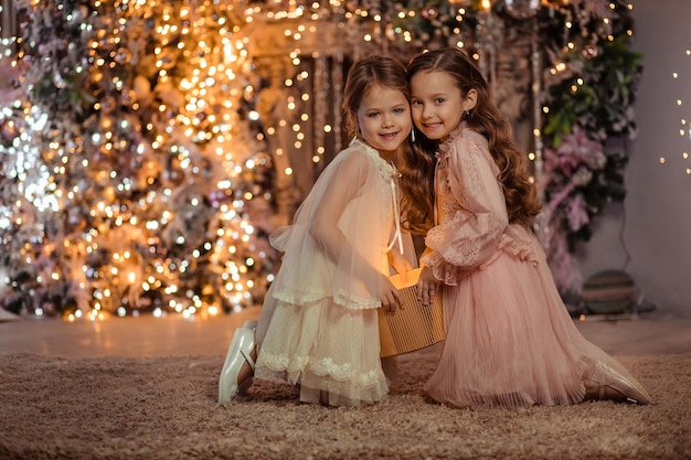 Joyeux Noël! Deux belles filles avec un cadeau magique à la maison près de l'arbre de Noël et de la cheminée