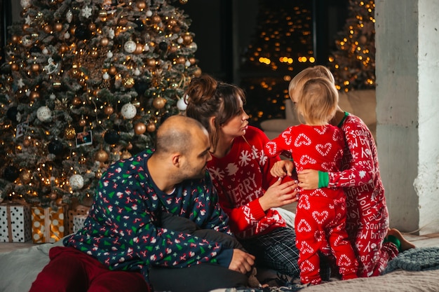 Joyeux Noël, famille heureuse, mère, père et enfants s'embrassant sur le lit le soir