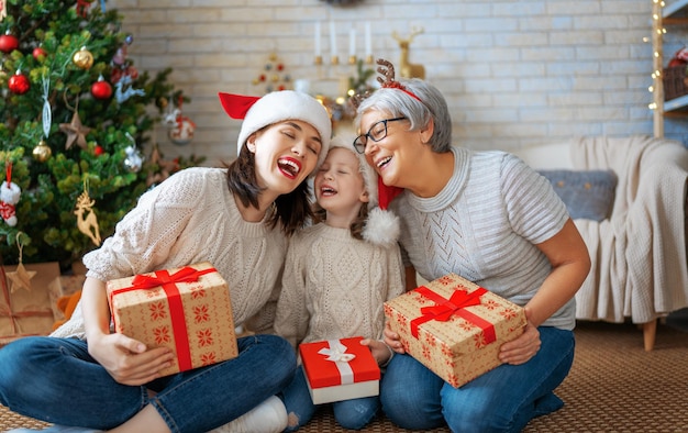 Joyeux Noël et joyeuses fêtes Enfant gai présentant des cadeaux à maman et grand-mère