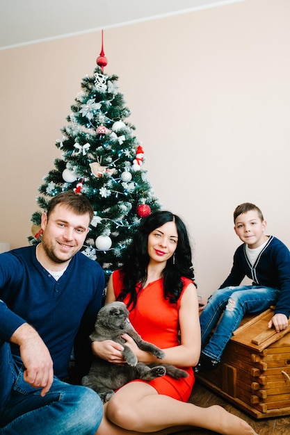 Joyeux Noël et joyeuses fêtes Jeune famille célébrant Noël à la maison près de l'arbre de Noël Heureuse maman papa et fils profitant de leurs vacances ensemble