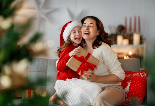 Joyeux Noël et Joyeuses Fêtes Maman joyeuse et sa fille mignonne échangent des cadeaux