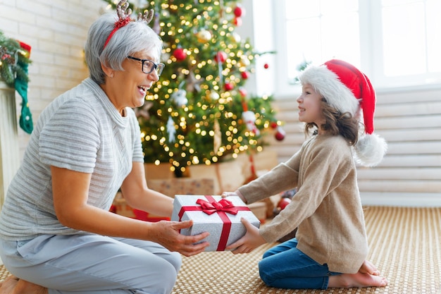 Joyeux Noël et joyeuses fêtes mamie et petit enfant s'amusant près de l'arbre à l'intérieur