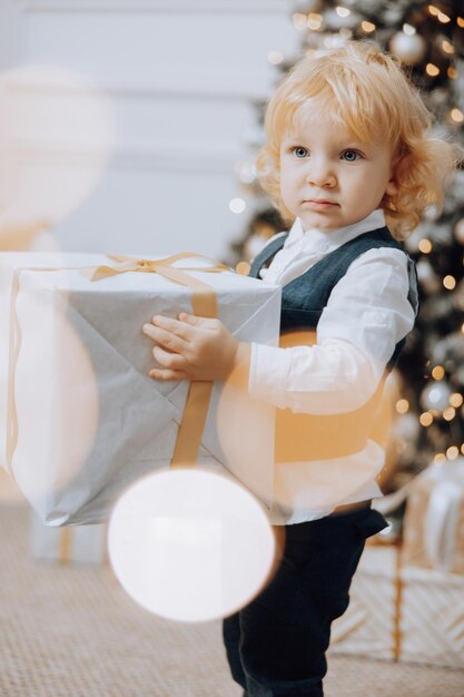 Joyeux Noël et Joyeuses Fêtes Petit garçon joyeux près de l'arbre de Noël avec des cadeaux de Noël Les enfants s'amusent Famille aimante avec des cadeau dans la chambre