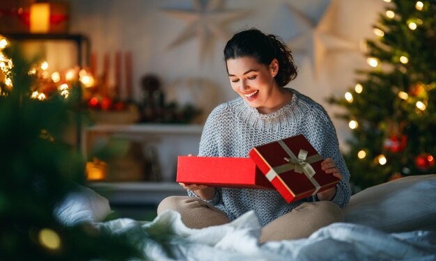 Photo joyeux noël joyeuses vacances surprise heureuse femme ouvrant un cadeau de noël