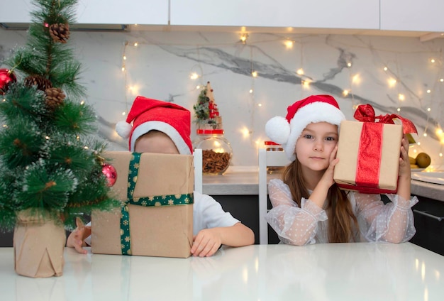 Joyeux Noël! De mignons petits enfants ouvrent des cadeaux de Noël magiques à la maison dans la cuisine. Salon décoré pour les vacances. Le concept de vacances, Noël et enfance. Mise au point sélective.