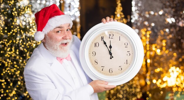 Joyeux Noël. nouvel an minuit. horloge indiquant presque minuit. temps de célébrer les vacances d'hiver. Dépêchez-vous. Le compte à rebours de Noël arrive. attendre les cadeaux de noël. santa man tenir réveil.