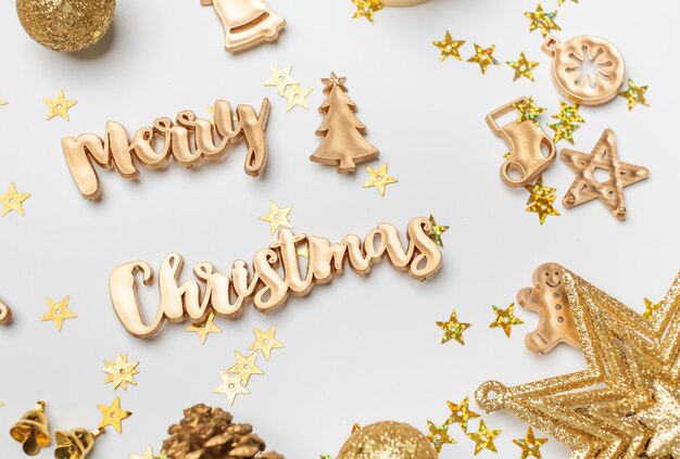 Joyeux Noël or texte brillant avec des articles de décoration de Noël de luxe sur table blanche