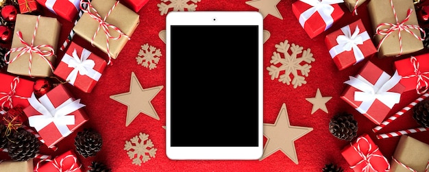 Joyeux Noël tablette ordinateur et boîte de cadeau avec ruban blanc sur fond de velours rouge