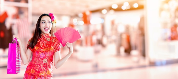 Joyeux Nouvel An chinois. Femme asiatique tenant une enveloppe rouge et un sac à provisions