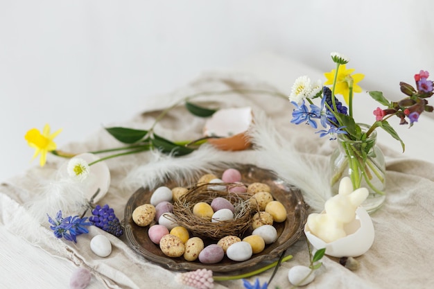 Joyeux Pâques œufs de chocolat de Pâques élégants dans le nid fleurs de printemps plumes et tissu de lin sur