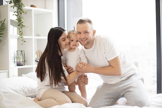 Joyeux parents dévoués embrassant leur fille dans la chambre