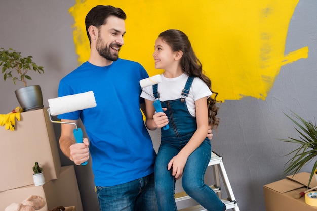 Joyeux père barbu et petite fille prévoient de peindre le mur