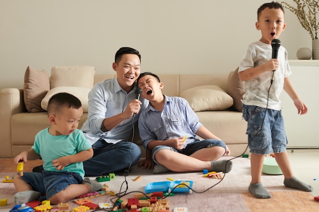 Joyeux père et fils asiatiques talentueux chantant dans des microphones à la maison