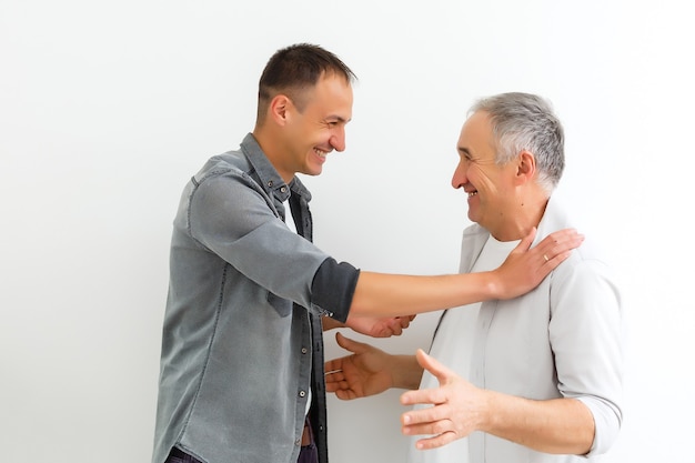 Joyeux Père Et Fils étreignant Et Posant Ensemble Isolés Sur Mur Blanc