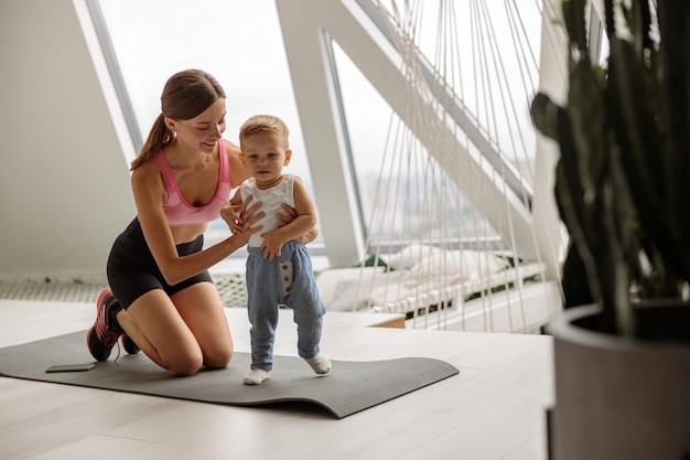 Joyeux petit bébé et maman faisant du sport à la maison