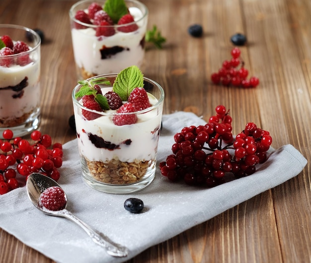 Joyeux petit-déjeuner yaourt avec muesli et baies sur une table en bois