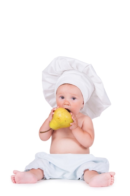 Joyeux petit enfant avec une poire dans ses mains dans un costume de chef sur un fond blanc.