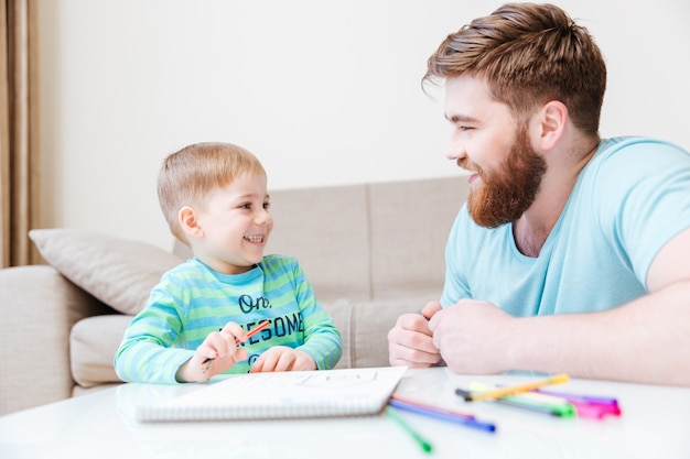 Joyeux petit fils et père dessinant et s'amusant à la maison