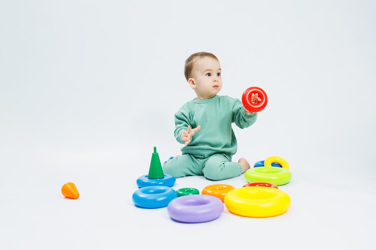 Photo joyeux petit garçon assis avec des jouets éducatifs en plastique sur fond blanc enfant et jouets pour le développement développement de la motricité des enfants