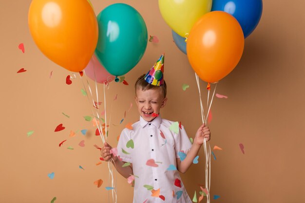 Joyeux petit garçon avec des ballons sur le fond beige