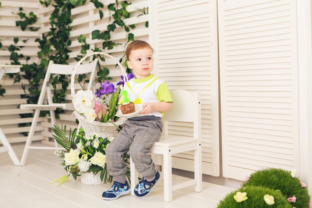 Joyeux petit garçon célébrant son anniversaire tient un morceau de gâteau, à l'intérieur. Fête d'anniversaire pour les enfants. Enfance insouciante, bonheur. Deux ans.