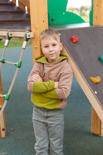 Un joyeux petit garçon grimpant sur une aire de jeux pour enfants. jeux de plein air. une promenade un jour d'été