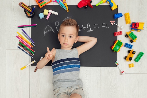 Joyeux petit garçon souriant se trouve sur son dessin