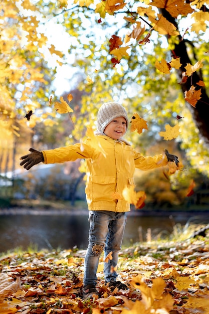 Un joyeux petit garçon souriant en veste jaune quitte le parc central de saint-pétersbourg en russie le soleil...