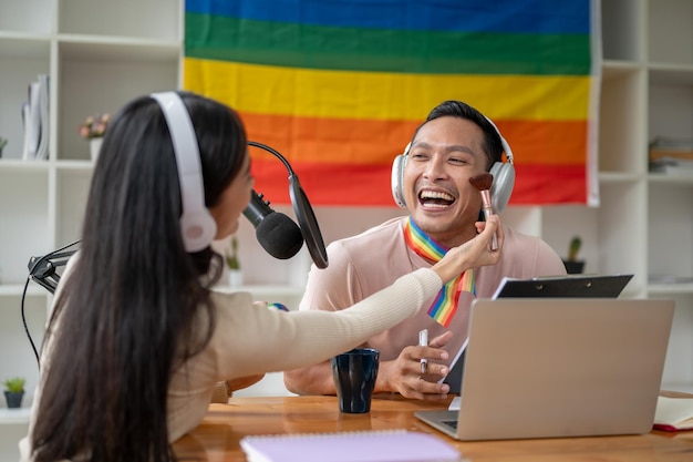 Un joyeux podcasteur ou animateur de radio gay asiatique est maquillé par une invitée dans son émission de radio