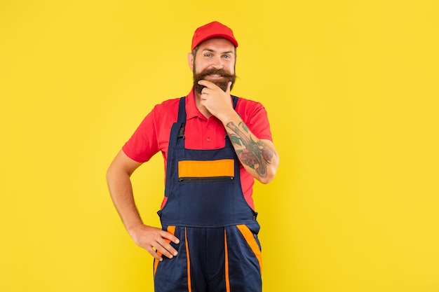 Joyeux réparateur d'homme barbu en vêtements de travail sur fond jaune