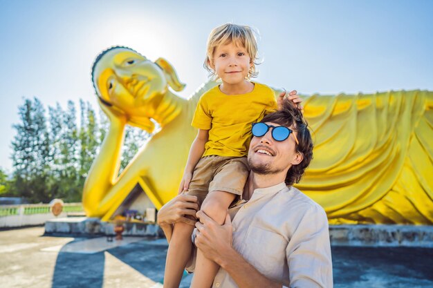 Joyeux touristes papa et fils sur fond de statue de Bouddha couché