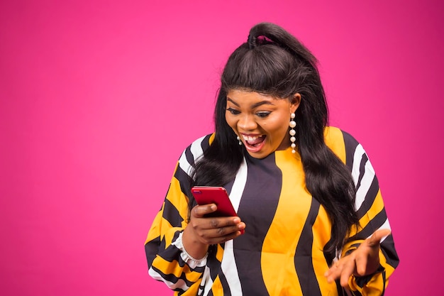 Joyful Black pluse size Female Using New Smartphone Standing Over Pink Background