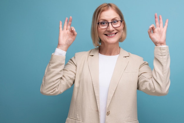 Joyful smiling s mature woman smiling on plain background with copy space