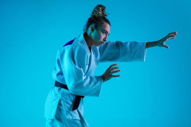 Judoist féminin professionnel posant isolé sur fond bleu studio en néon