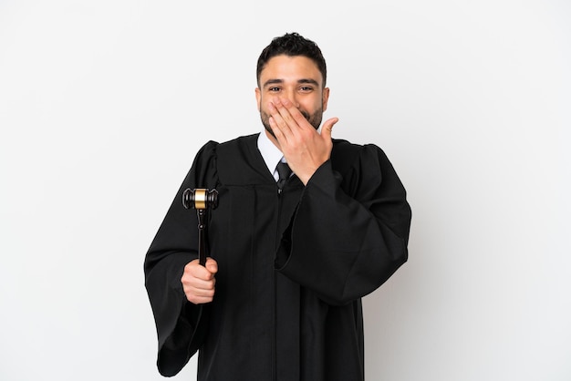 Juge homme arabe isolé sur fond blanc heureux et souriant couvrant la bouche avec la main