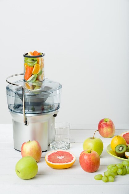 Photo juiceuse électrique moderne et fruits variés sur le comptoir de la cuisine concept de mode de vie sain