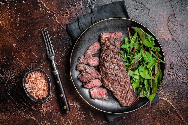 Juicy Grilled Machete jupe steak de viande de boeuf sur assiette avec salade Fond sombre Vue de dessus