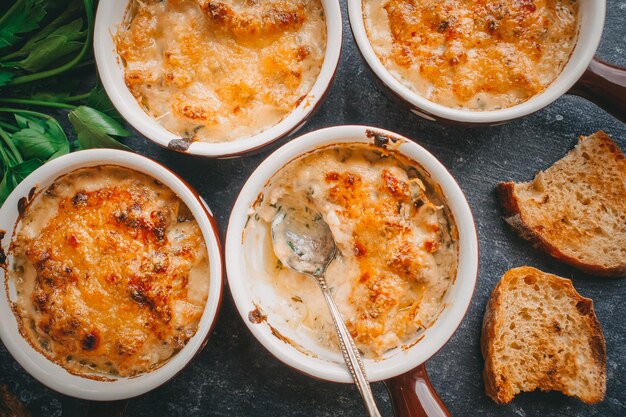 Julienne en portions, Champignons à la crème et au fromage, Nourriture de restaurant sur fond sombre