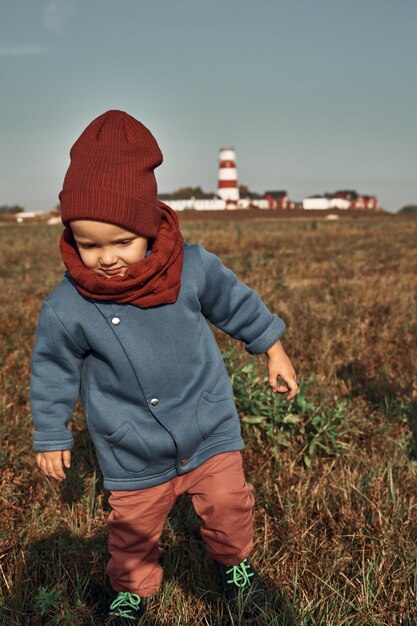 Des jumeaux jouent au ballon sur le terrain, un phare en arrière-plan, des enfants de deux ans. Promenades d'automne dans la nature.