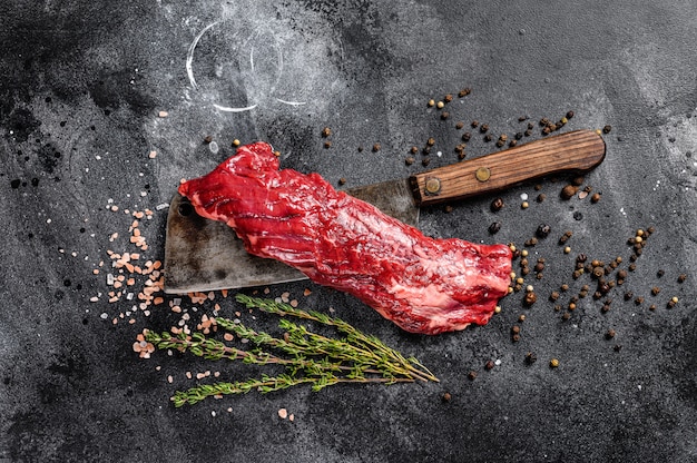 Photo jupe crue, steak de machette sur un couperet à viande. surface noire. vue de dessus