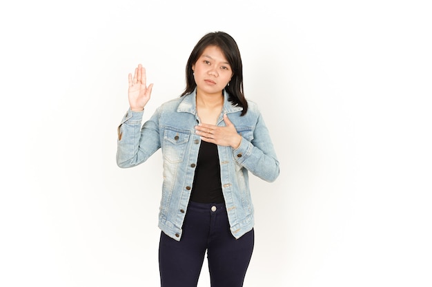 Jurer de belle femme asiatique portant une veste en jean et une chemise noire isolée sur fond blanc