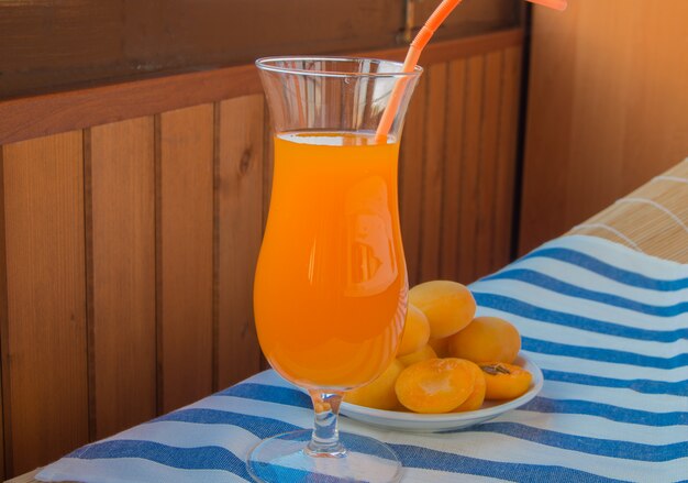 Jus d&#39;abricot dans un verre avec paille et fruits frais sur serviette