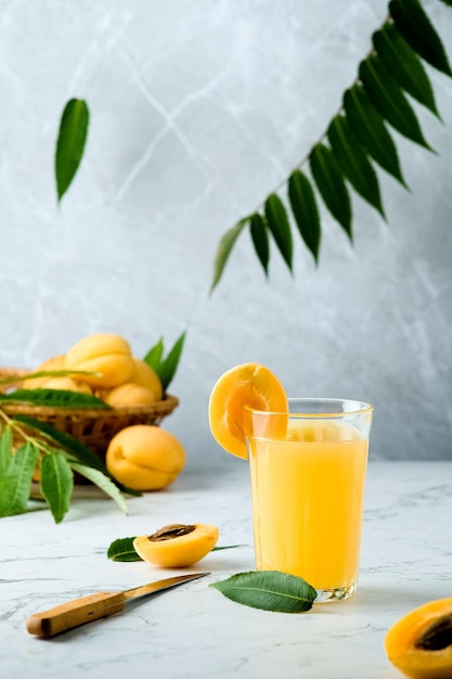 le jus d'abricot frais contient de nombreuses vitamines, abricot et jus, brindilles vertes en arrière-plan, froid d