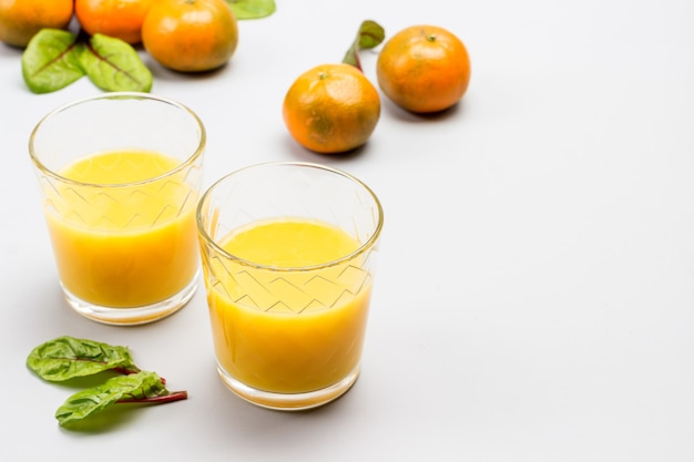 Jus d'agrumes dans des verres. Mandarines avec feuilles sur table