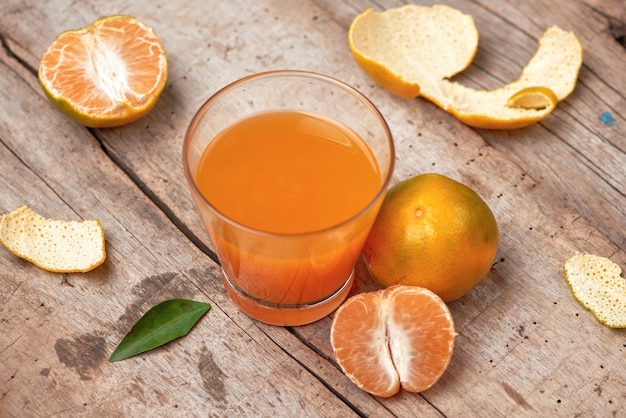 Jus d'agrumes en verre et mandarine fraîche sur fond de bois