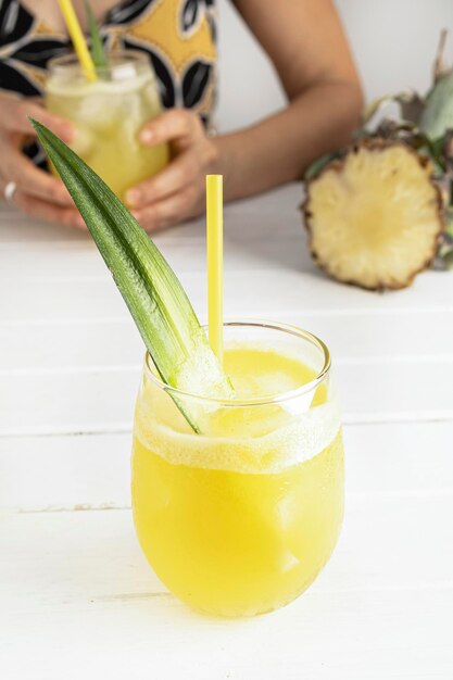 Jus d'ananas fait maison rafraîchissant avec de la glace Fille à une table buvant un jus d'ananas